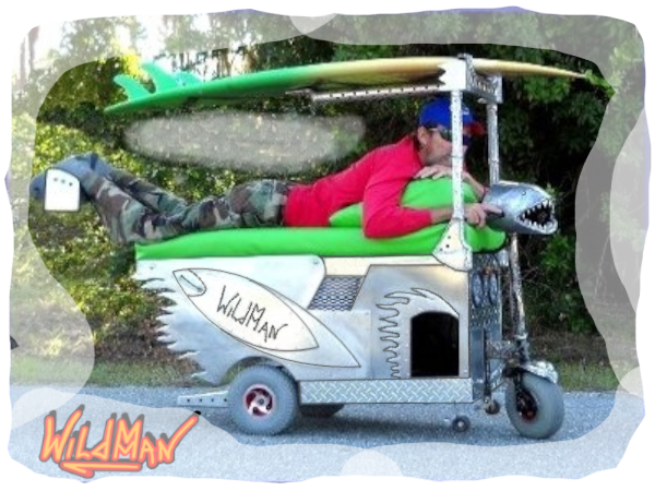 The Surf Kart is a three wheeled prone position mobility device. It has a surfboard roof and aluminum surfboards with flames flowing from the rear. The side door has raised letters of aluminum which read IGMA which is short for It Gets Me Around.